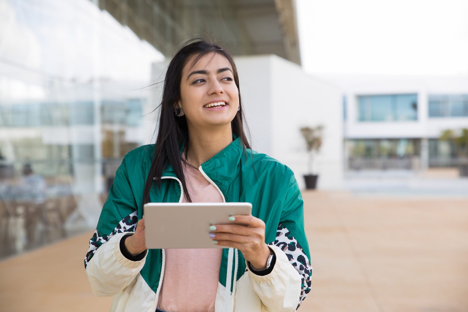 Front view of woman holding tablet in hand, looking aside Study Abroad